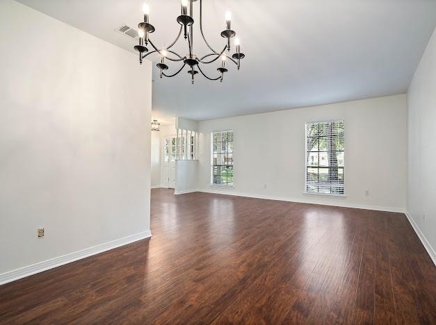 unfurnished room with an inviting chandelier and dark hardwood / wood-style floors