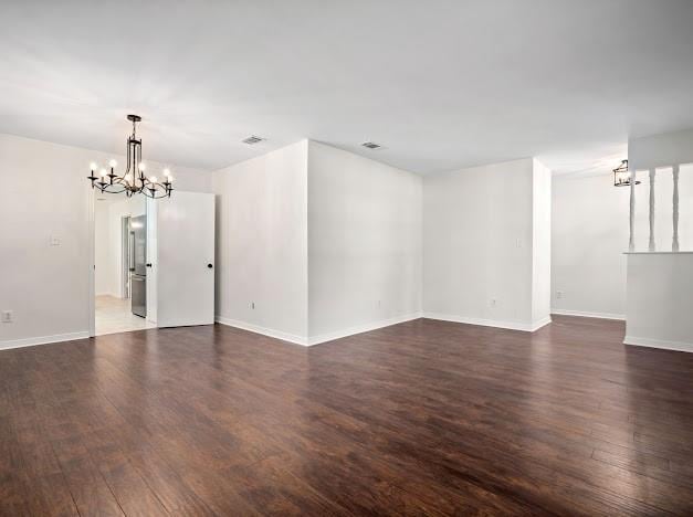 unfurnished room with dark wood-type flooring and an inviting chandelier