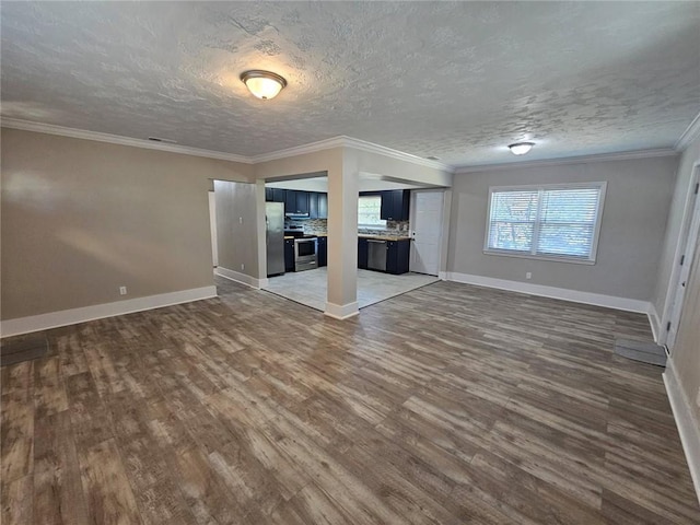 unfurnished living room with baseboards, a textured ceiling, ornamental molding, and wood finished floors