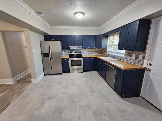 kitchen with butcher block counters, blue cabinets, stainless steel appliances, under cabinet range hood, and visible vents