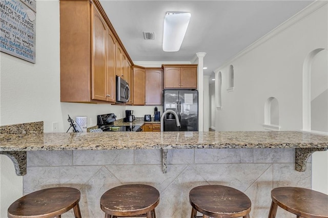 1385 Beach Blvd W, Gulf Shores, AL 36542 - kitchen featuring kitchen peninsula, light stone counters, ornamental molding, a breakfast bar, and appliances with stainless steel finishes