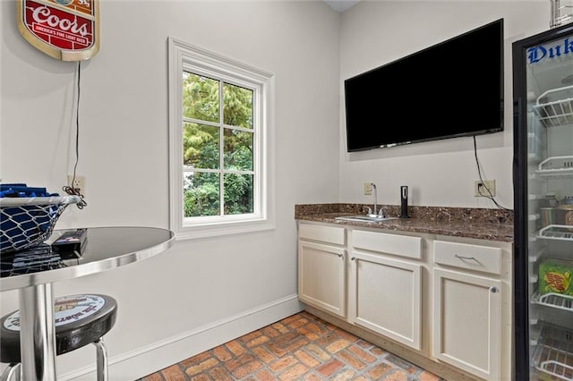 interior space featuring dark stone countertops, white cabinetry, and sink