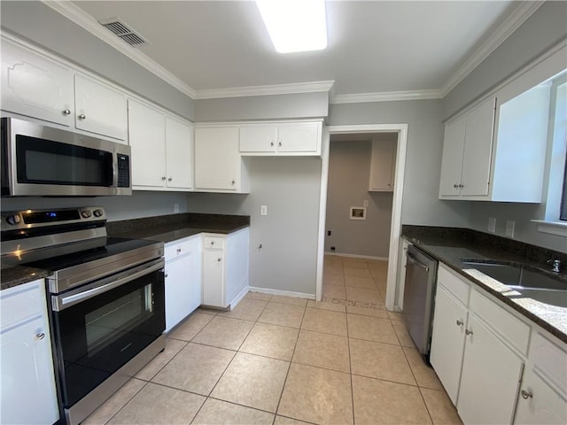 kitchen with appliances with stainless steel finishes, sink, white cabinets, light tile patterned floors, and crown molding