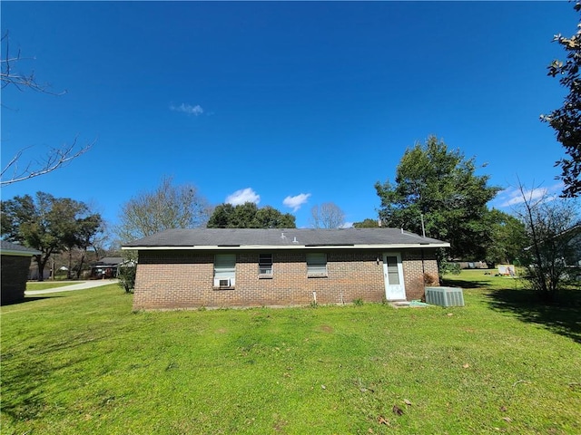 back of property featuring a yard, brick siding, and central AC unit