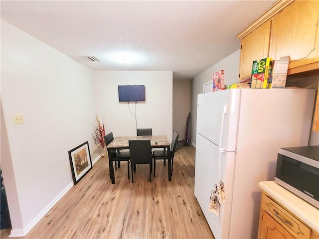 dining space with visible vents, baseboards, a textured ceiling, and light wood finished floors