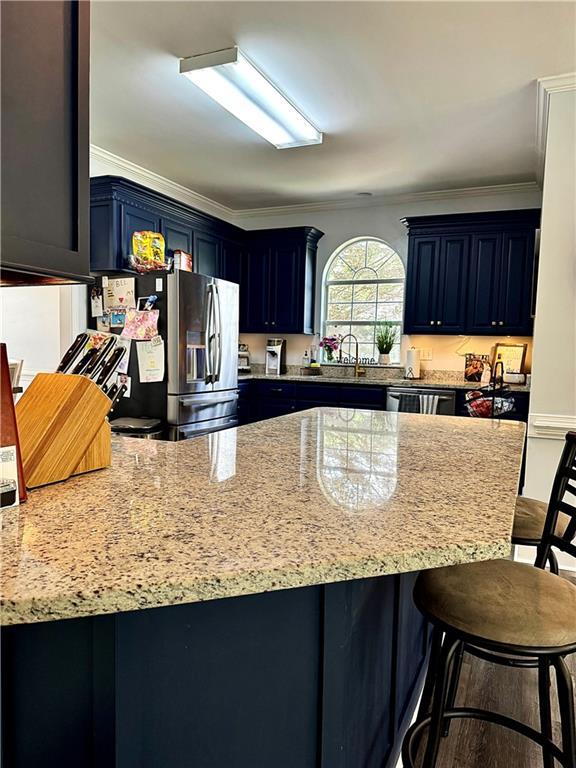 2200 Orourke Dr, Mobile, AL 36695 - kitchen featuring stainless steel fridge, ornamental molding, light stone counters, a breakfast bar, and a peninsula