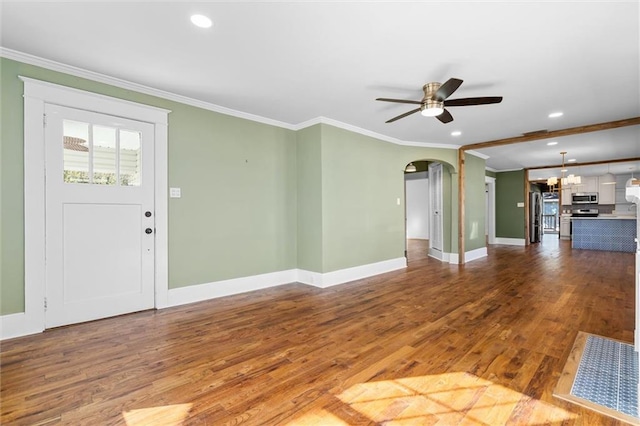 unfurnished living room with ceiling fan, arched walkways, wood finished floors, and crown molding