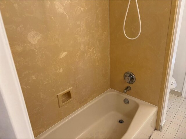 bathroom featuring tile patterned flooring, toilet, and washtub / shower combination