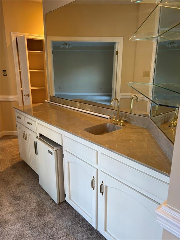 kitchen with white cabinets, a sink, dishwashing machine, and dark carpet