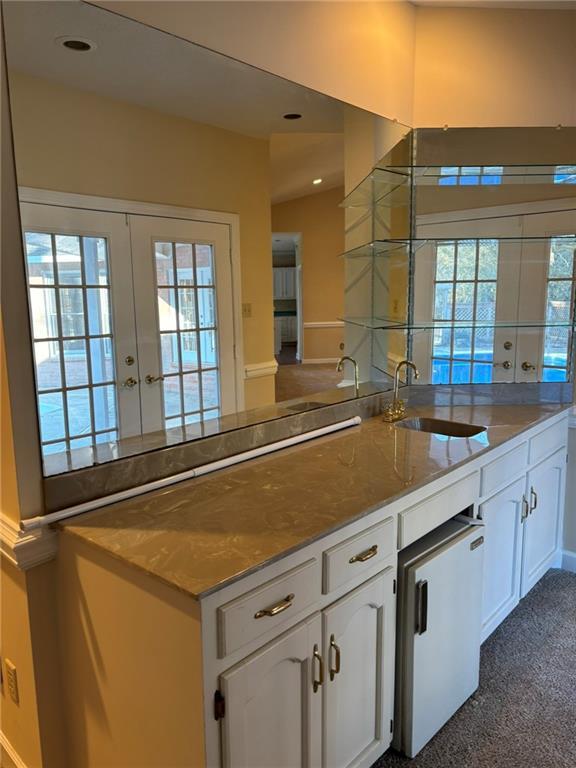 kitchen featuring french doors, white cabinets, a sink, and a healthy amount of sunlight
