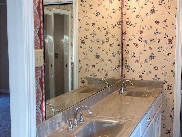 full bathroom with double vanity, wallpapered walls, and a sink