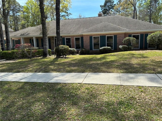single story home with a front yard, roof with shingles, and a chimney