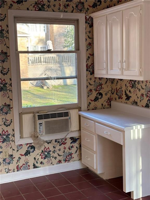 kitchen featuring cooling unit, white cabinetry, wallpapered walls, and tile patterned flooring