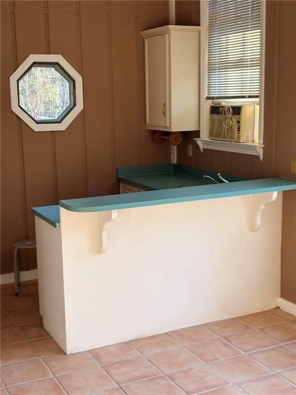 kitchen with a kitchen breakfast bar, light tile patterned floors, a peninsula, and cooling unit