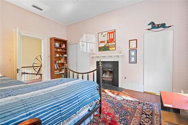 26 Julia St S, Mobile, AL 36604 - bedroom featuring wood finished floors, wallpapered walls, and a fireplace with flush hearth