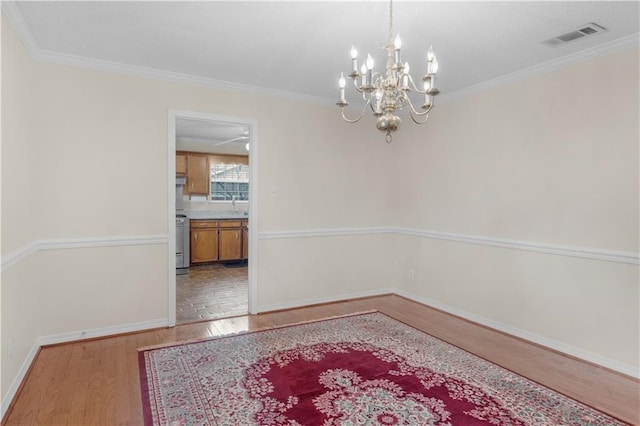 dining room with visible vents, ornamental molding, wood finished floors, an inviting chandelier, and baseboards