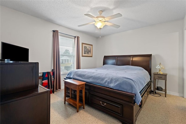 bedroom featuring ceiling fan, light colored carpet, and a textured ceiling