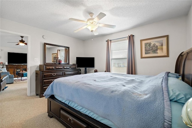 bedroom with ceiling fan, light colored carpet, and a textured ceiling