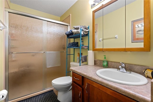 bathroom featuring vanity, a textured ceiling, a shower with door, and toilet