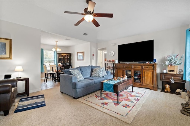 carpeted living room featuring ceiling fan with notable chandelier