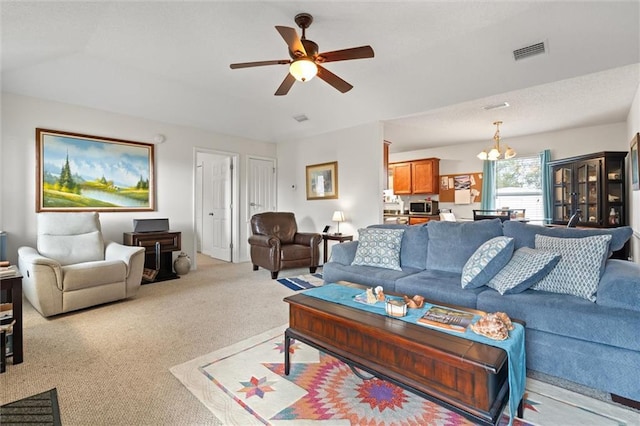 carpeted living room with ceiling fan with notable chandelier