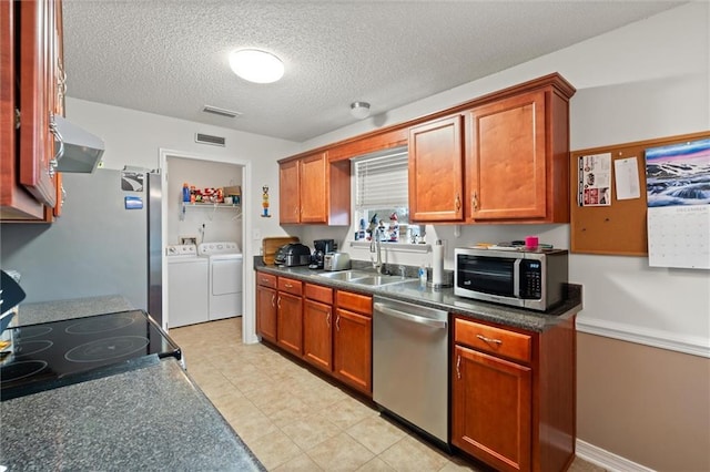 kitchen with sink, appliances with stainless steel finishes, range hood, washing machine and dryer, and a textured ceiling