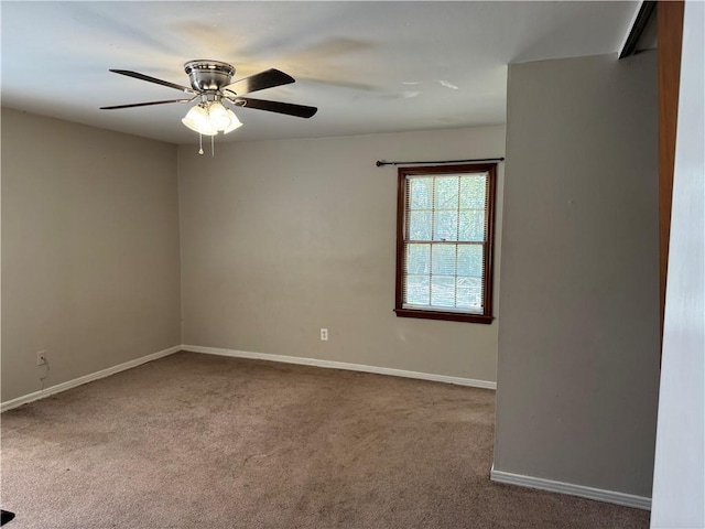 carpeted spare room featuring ceiling fan and baseboards