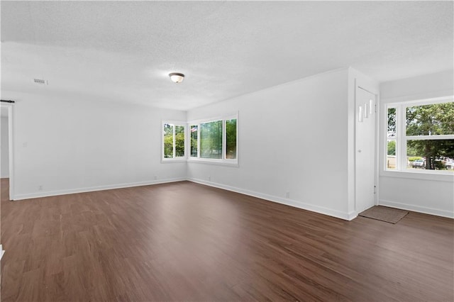 unfurnished room featuring baseboards, a textured ceiling, dark wood finished floors, and visible vents