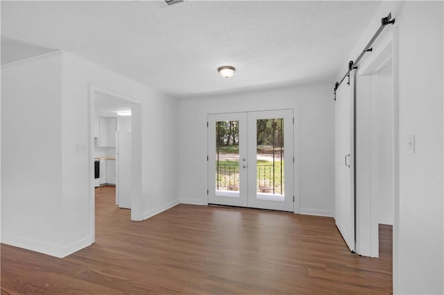 interior space with baseboards, french doors, a barn door, and wood finished floors