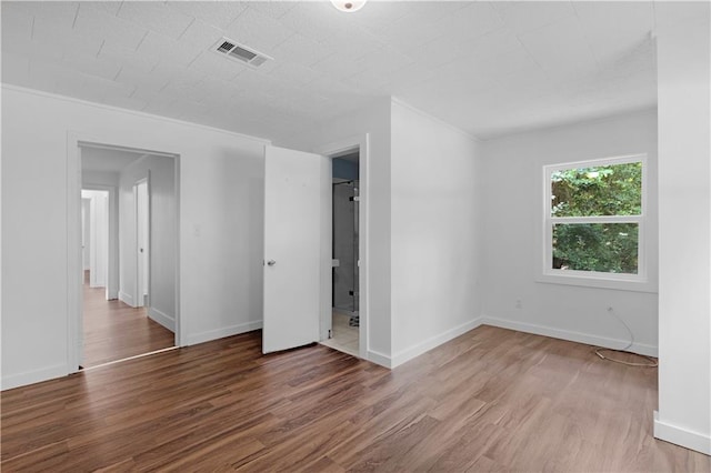 unfurnished bedroom with crown molding, baseboards, visible vents, and wood finished floors