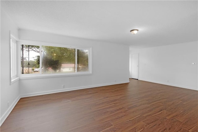 spare room with baseboards, dark wood-style floors, and a textured ceiling
