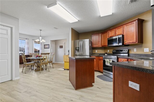 kitchen featuring stainless steel appliances, a kitchen island, a sink, light wood finished floors, and an inviting chandelier