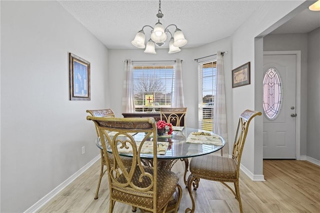 dining area featuring light wood-style floors, a chandelier, and a textured ceiling