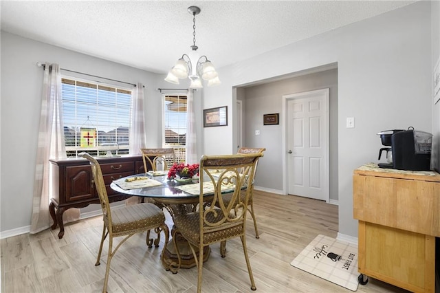 dining area featuring a textured ceiling, light wood finished floors, baseboards, and an inviting chandelier