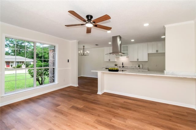 kitchen with island exhaust hood, light countertops, a chandelier, ceiling fan, and baseboards