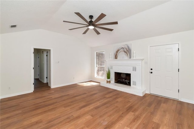 unfurnished living room featuring ceiling fan, vaulted ceiling, light wood finished floors, a brick fireplace, and baseboards