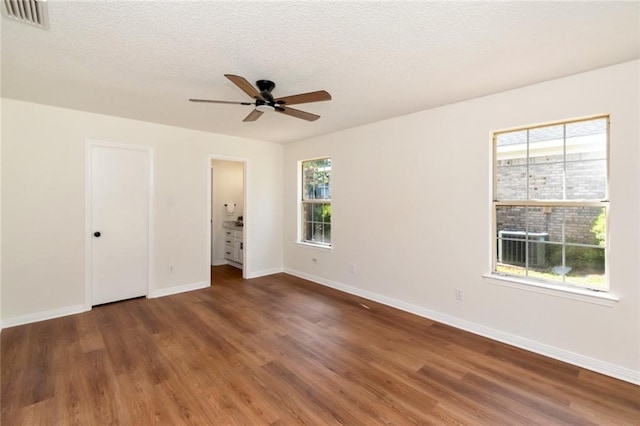 unfurnished bedroom with wood finished floors, baseboards, multiple windows, and a textured ceiling