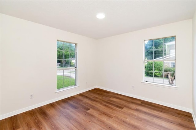 unfurnished room with baseboards, wood finished floors, and recessed lighting