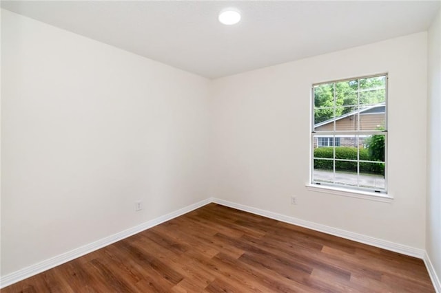 spare room featuring baseboards and wood finished floors