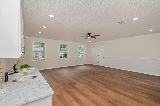 unfurnished living room featuring a sink, a textured ceiling, recessed lighting, light wood-style floors, and a ceiling fan