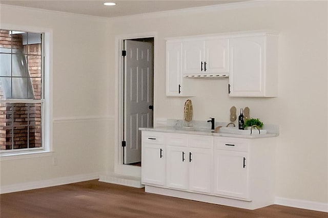 bar area with wood finished floors, baseboards, and crown molding