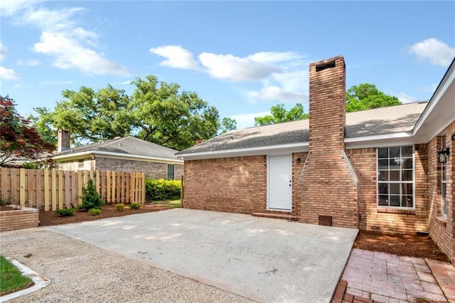 back of property with a patio, fence, a chimney, brick siding, and a shingled roof