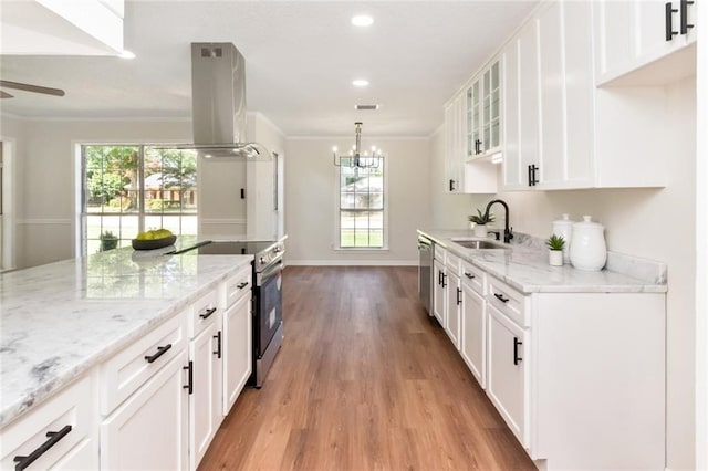 kitchen with electric range oven, island exhaust hood, light wood-type flooring, crown molding, and healthy amount of natural light