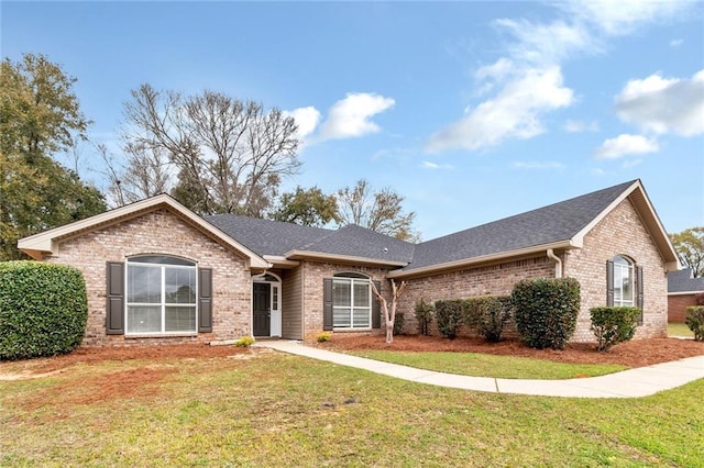 ranch-style home with brick siding, a front lawn, and roof with shingles