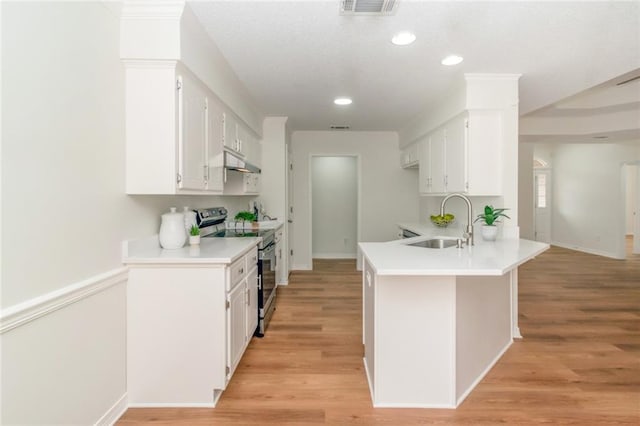 kitchen with under cabinet range hood, light countertops, electric stove, white cabinets, and a sink