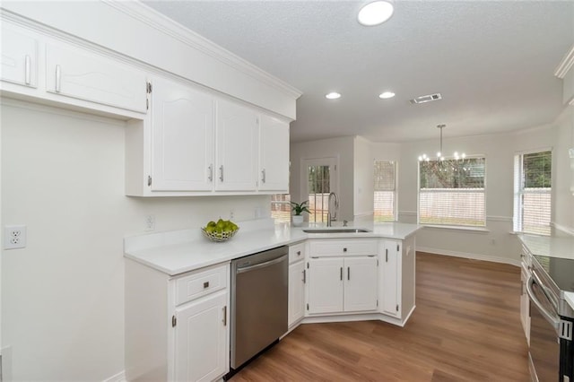 kitchen with visible vents, appliances with stainless steel finishes, a peninsula, white cabinetry, and a sink