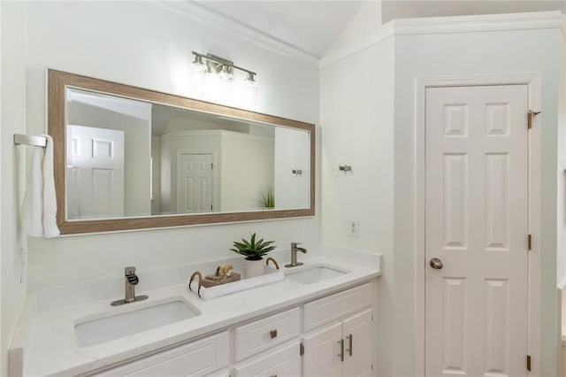 bathroom featuring double vanity, ornamental molding, lofted ceiling, and a sink