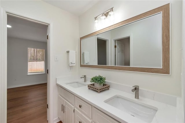 full bathroom with double vanity, wood finished floors, baseboards, and a sink