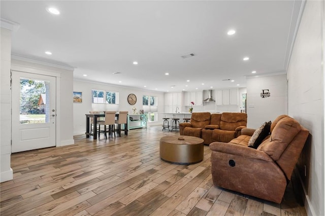 living room with light wood-type flooring and ornamental molding