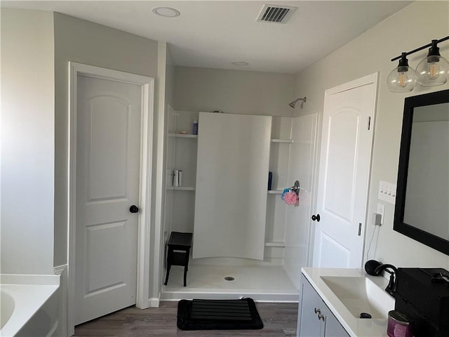 bathroom featuring independent shower and bath, hardwood / wood-style floors, and vanity